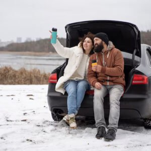 Couple sitted on car backside and enjoy the snow Weather